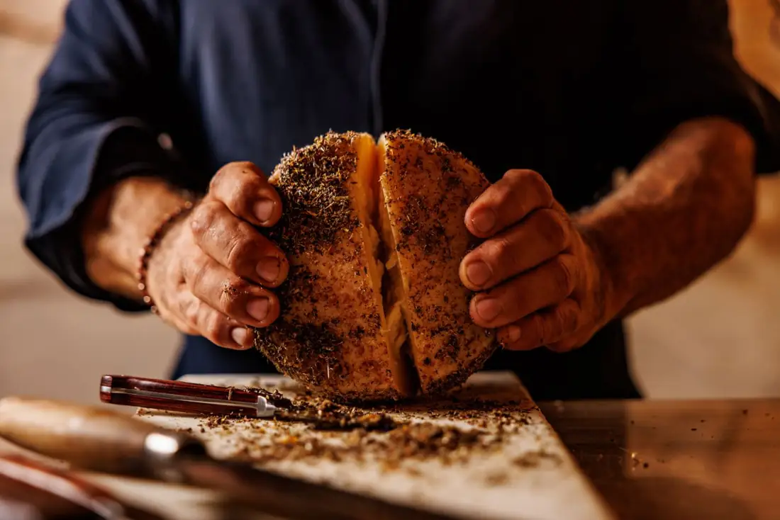 Le mani che aprono una forma con la crosta alle erbe
